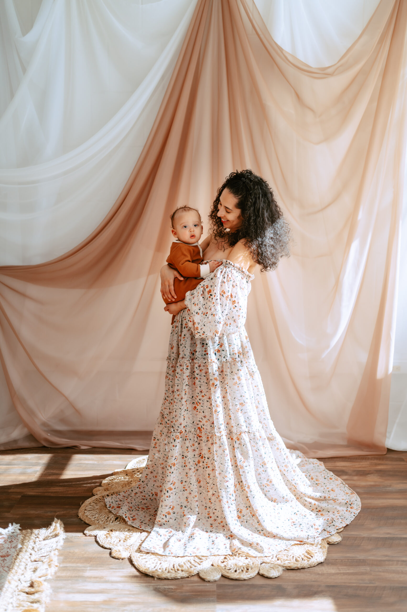 Mother holding 10-month-old baby during Spring motherhood mini session at Annapolis natural light studio, both wearing client closet outfits with soft neutral backdrops