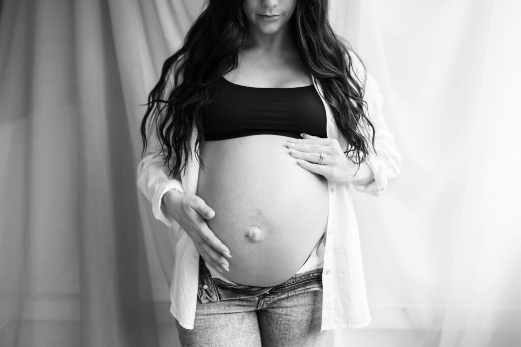 woman with long flowing hair holds her pregnant belly