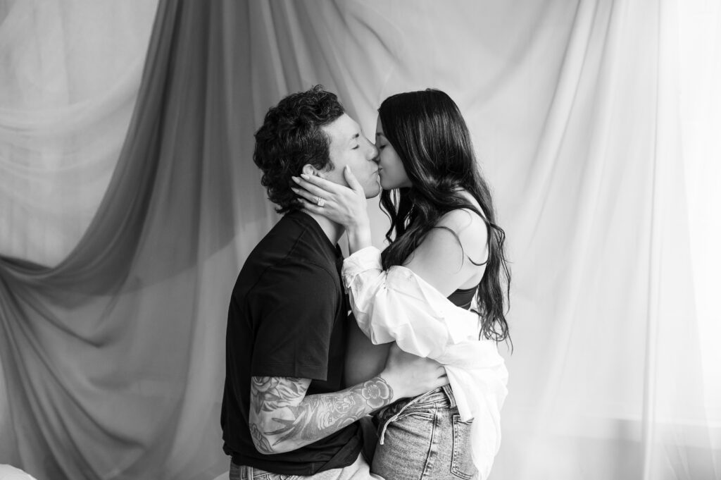 couple kisses in a photography studio, her hands on his cheeks, his hands on her hips