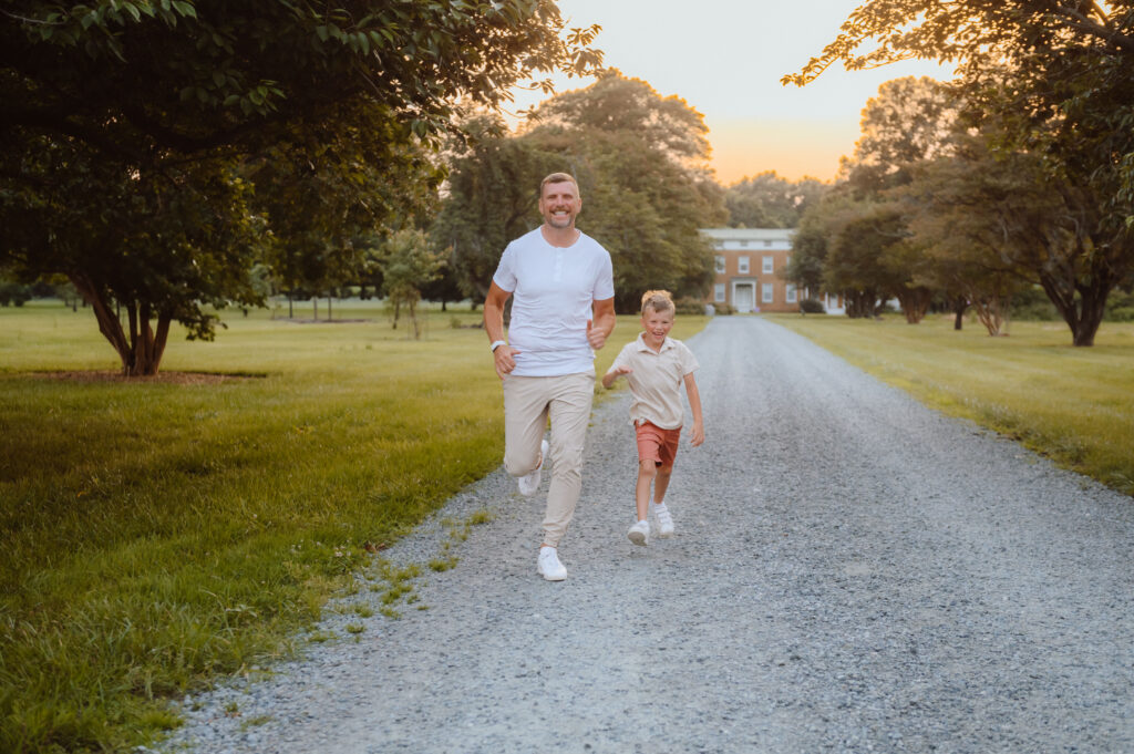 Father and son running down gravel lane in front of farmhouse