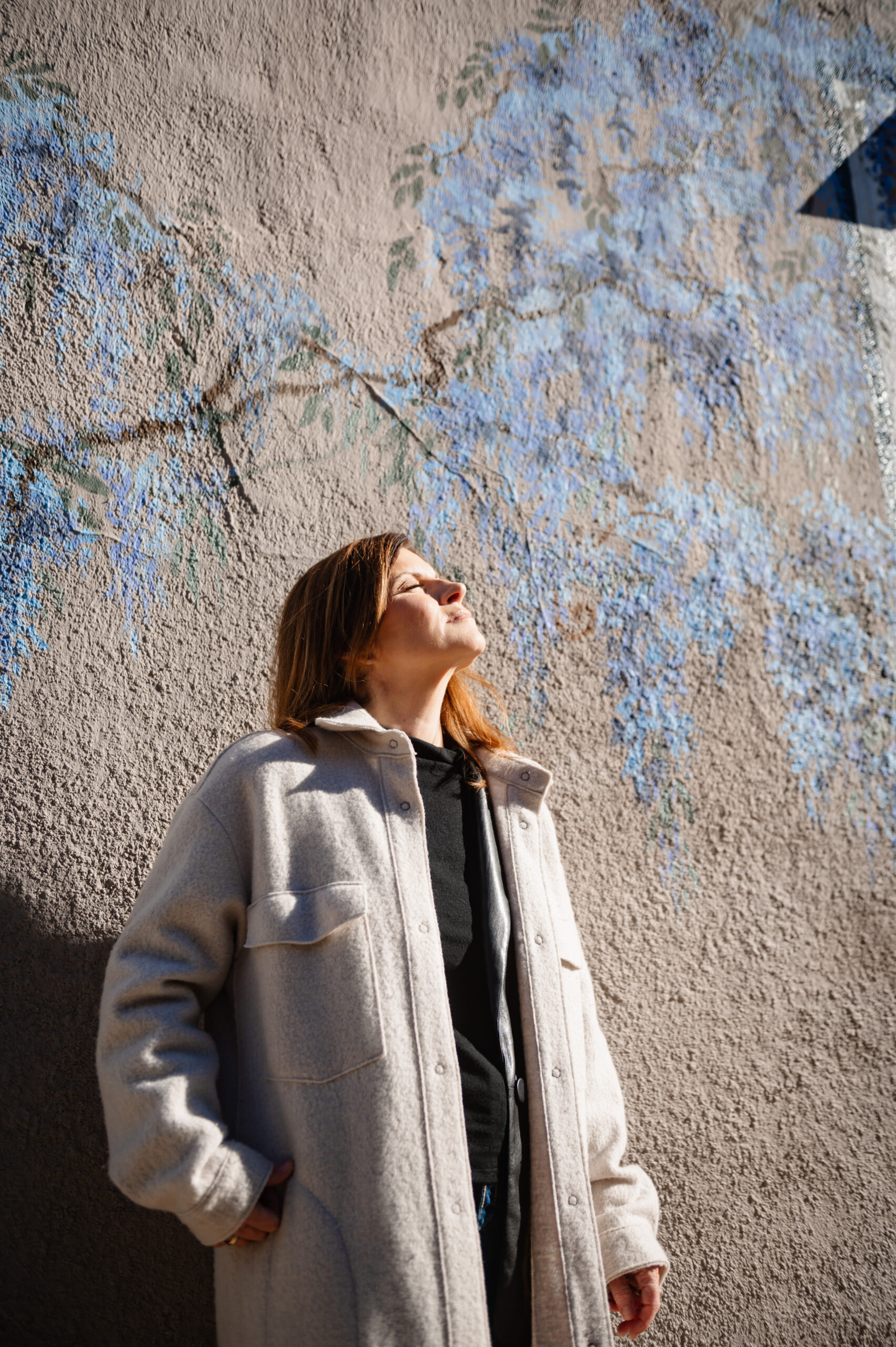 woman stands in harsh light with her face to the sun