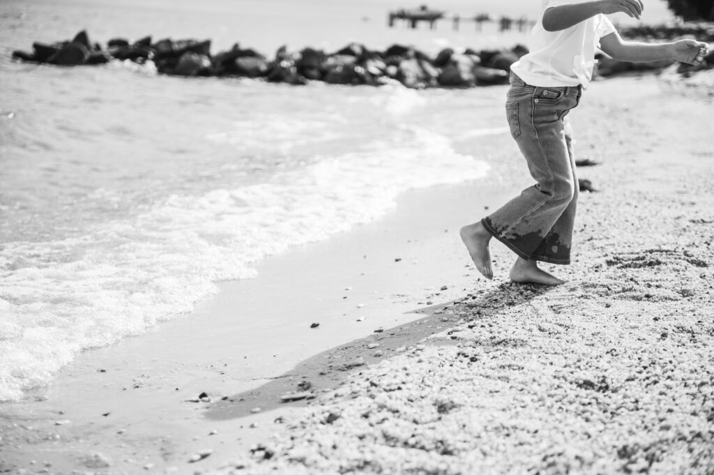 black and white candid photo of a child's legs/feet running from a wave