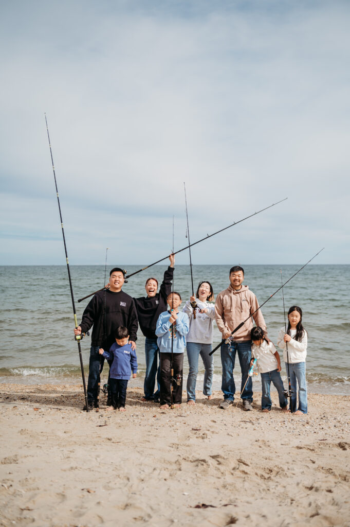 photo of two families of 4 each holding fishing poles with their backs to the cheseapeake bay, they are candid but it has a timeless and nostalgic essence to the image