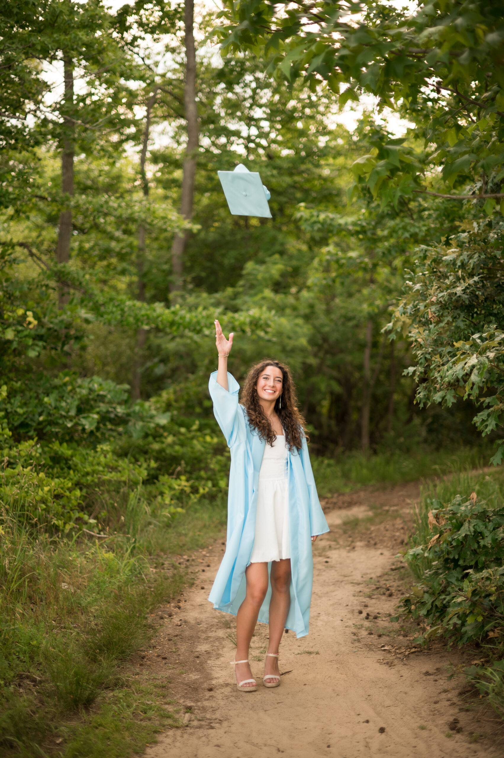 graduate in her graduation robe tosses her cap in the air