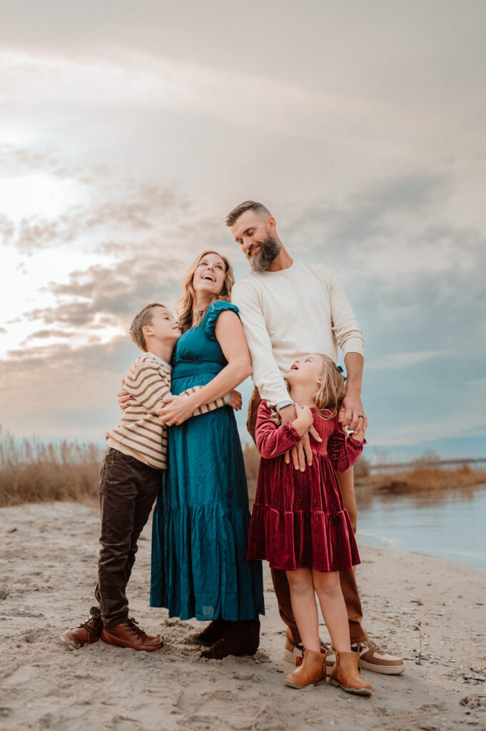 Family of four sharing a candid laughing moment on the beach during an Annapolis Maryland fall session 