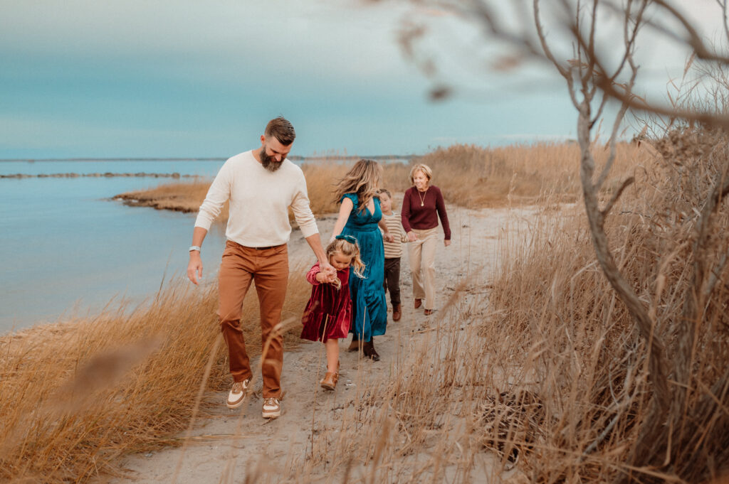 Extended family walking together along a coastal marsh trail during a fall family session