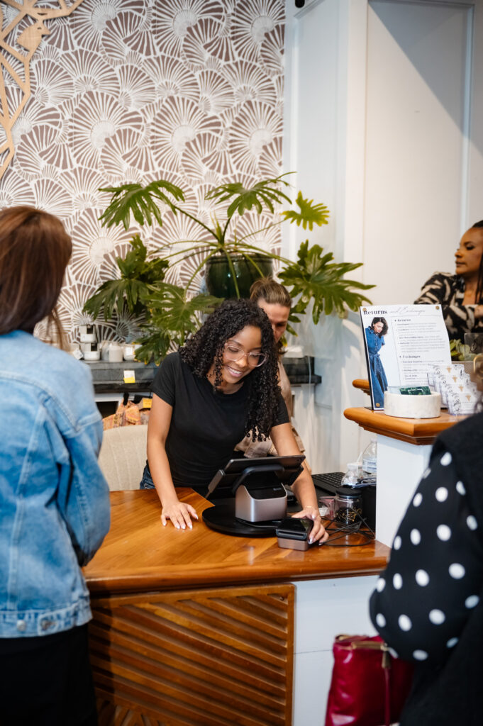 Bohemian Black staff member smiling at the checkout counter during the busy Hello Spring fashion show event