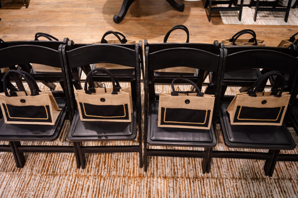Row of gift bags on black folding chairs lined up along the runway at Bohemian Black boutique event in Annapolis
