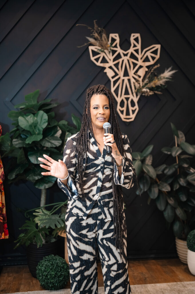 Local business photographer features Rose, owner of Bohemian Black, gesturing while emceeing the Hello Spring fashion show at Annapolis Town Center boutique