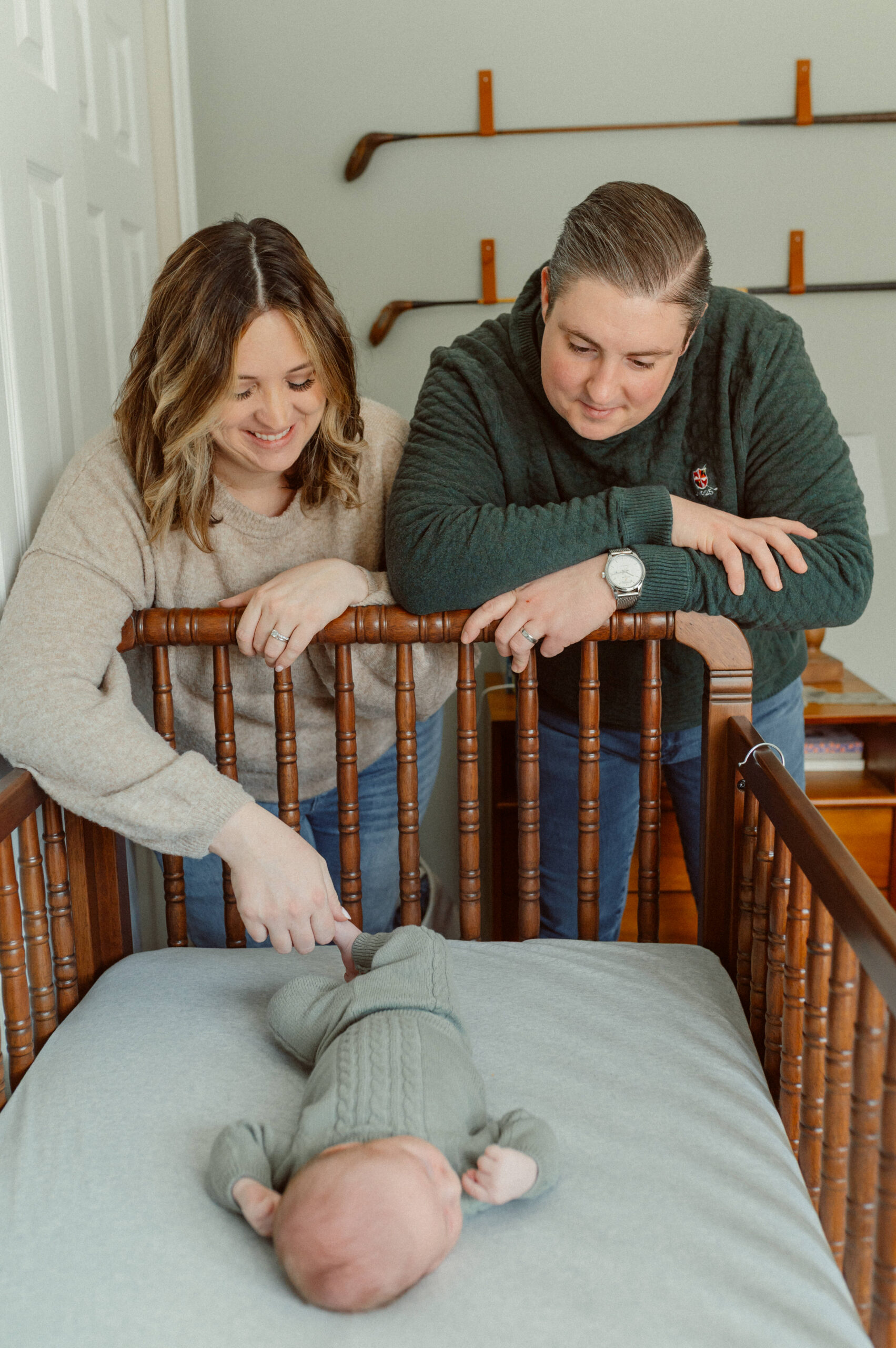 Annapolis newborn photographer capturing parents with baby in nursery crib